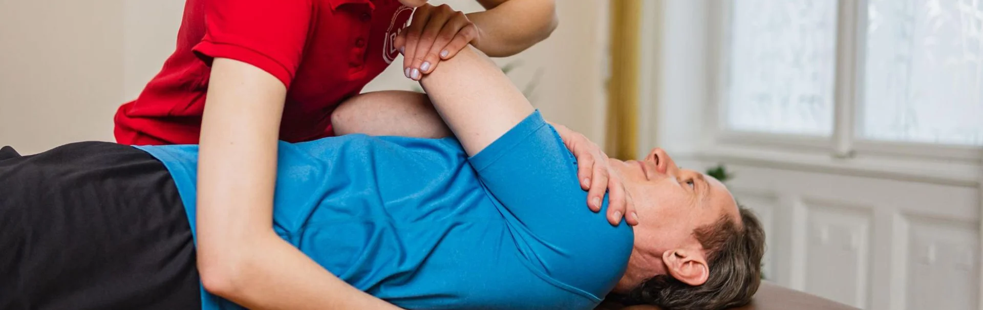Fizioterapeuta kezeli a páciens vállát felsővégtagi artroszkópos műtét (váll artroszkópia, könyök artroszkópia, csukló artroszkópia) utáni rehabilitáció során.